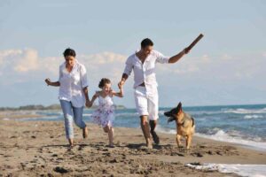 famiglia corre sulla spiaggia con il proprio cane