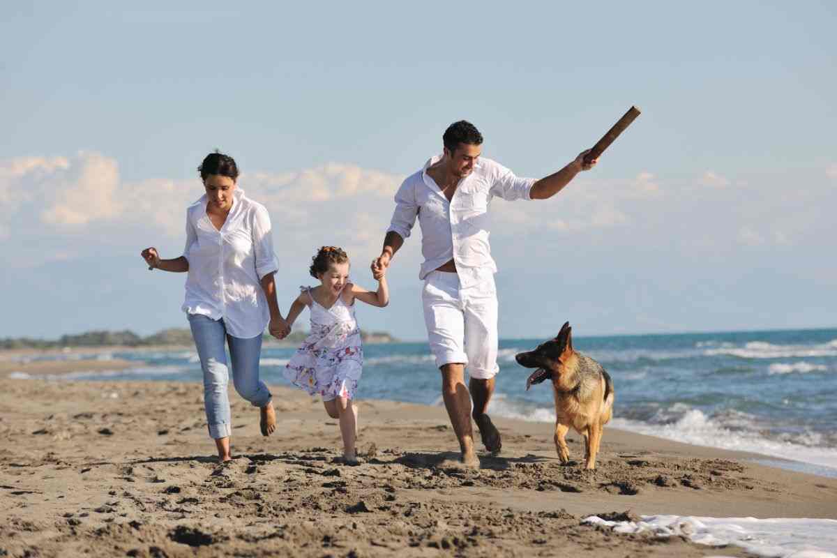 famiglia corre sulla spiaggia con il proprio cane